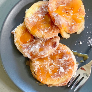 apple fritters on black plate with fork