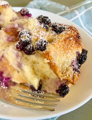 Blueberry cream cheese French toast on a white plate with a fork on the side