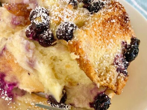 Blueberry cream cheese French toast on a white plate with a fork on the side