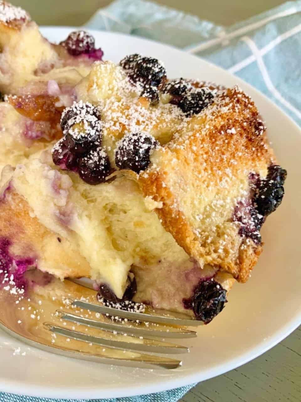 Blueberry cream cheese French toast on a white plate with a fork on the side