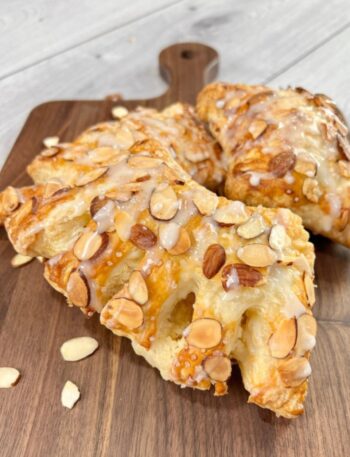 2 bear claw pastries sitting on a dark wood board