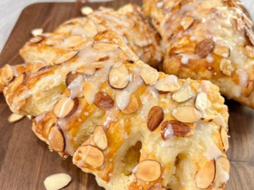 2 bear claw pastries sitting on a dark wood board