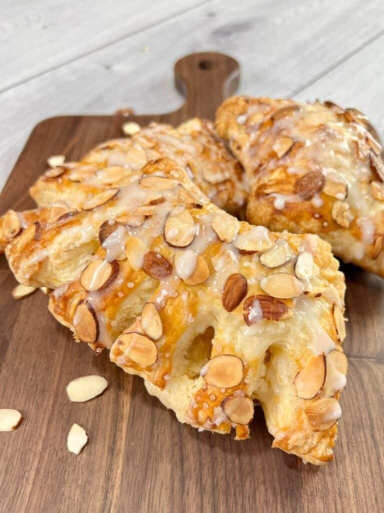 2 bear claw pastries sitting on a dark wood board