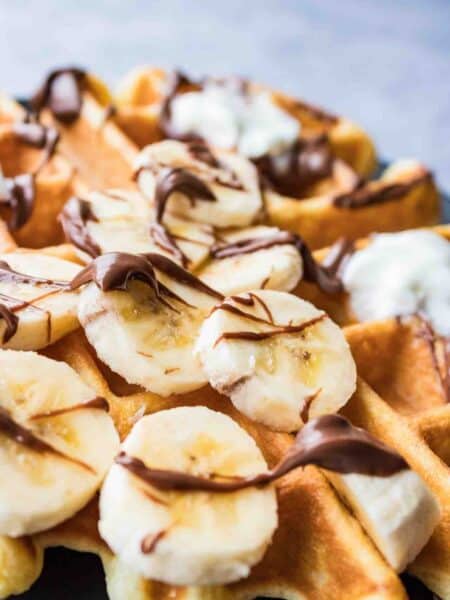 Waffle topped with banana slices, Nutella and whipping cream