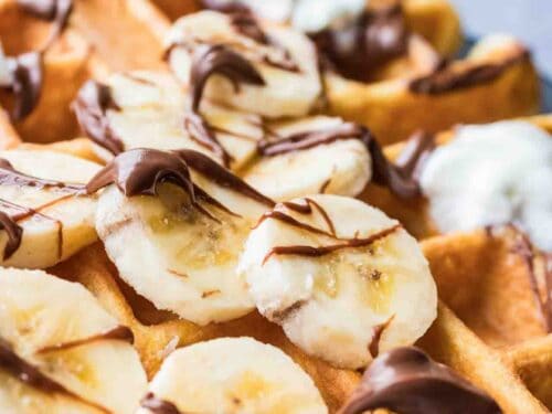 Waffle topped with banana slices, Nutella and whipping cream