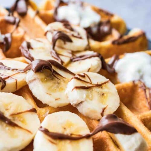 Waffle topped with banana slices, Nutella and whipping cream