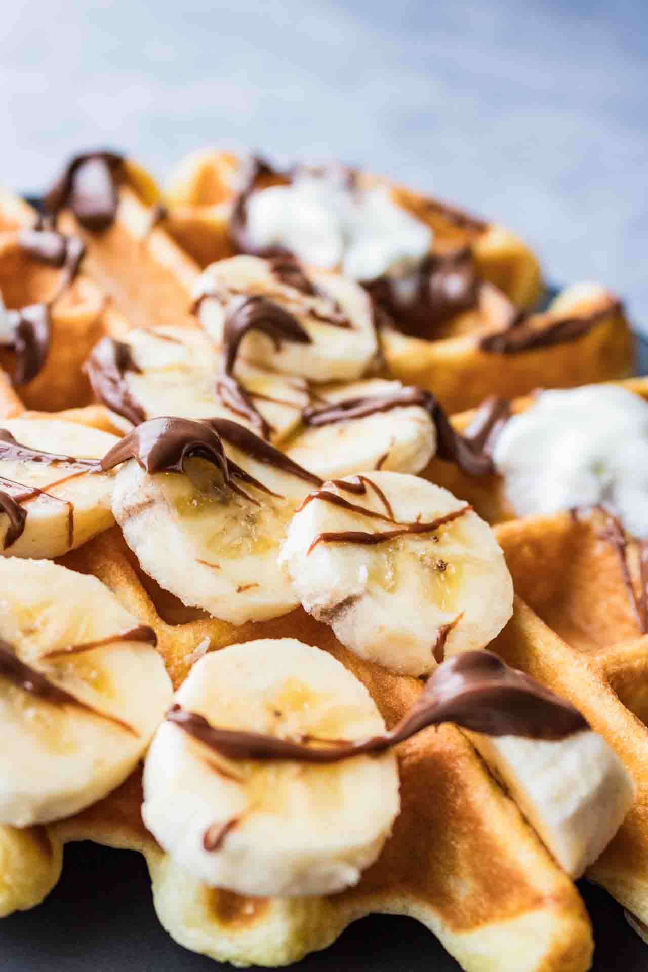 Waffle topped with banana slices, Nutella and whipping cream