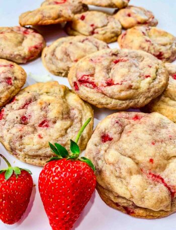 laid out strawberry cheesecake cookies with 2 whole strawberries