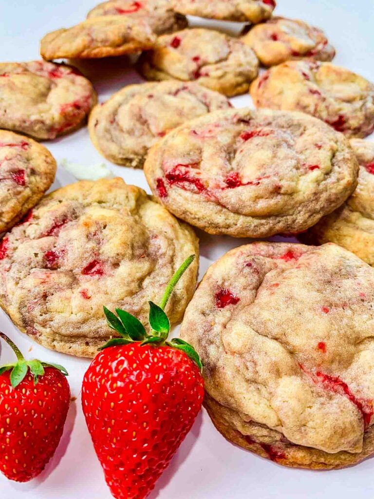 laid out strawberry cheesecake cookies with 2 whole strawberries