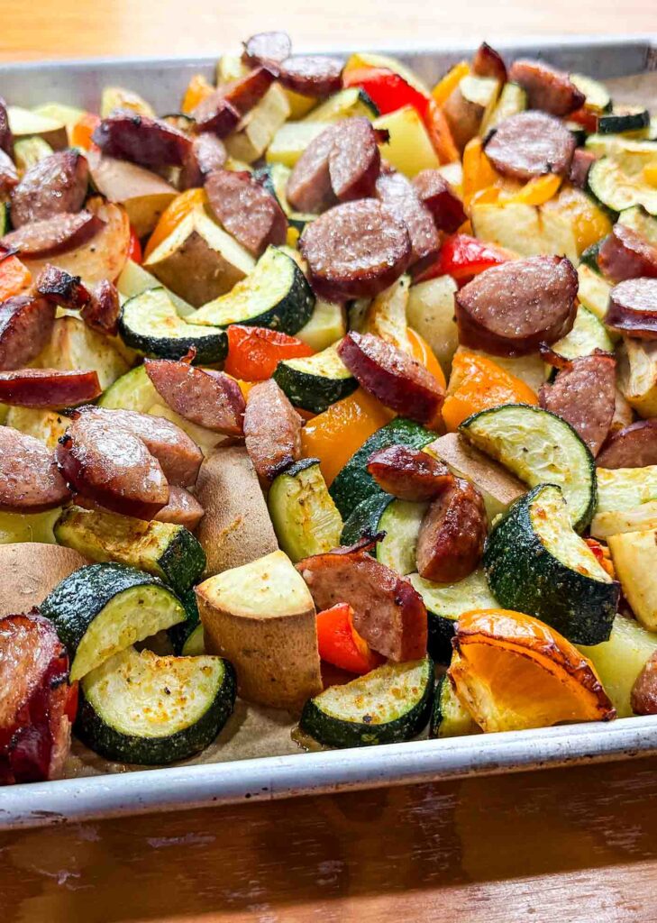 a sheet full of veggies and kielbasa sausage on top