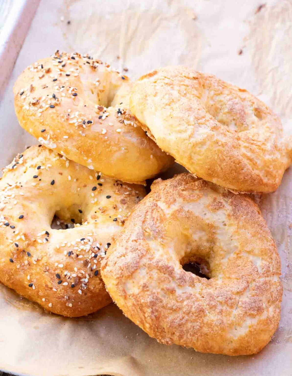 4 Healthy Greek Yogurt Protein Bagels on parchment paper with everything seasoning and cinnamon sugar.