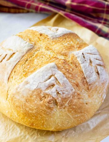 A round crusty bread on a brown parchment paper on a counter