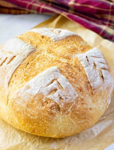 A round crusty bread on a brown parchment paper on a counter