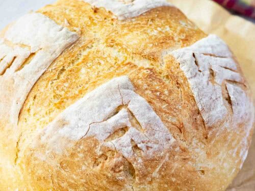A round crusty bread on a brown parchment paper on a counter
