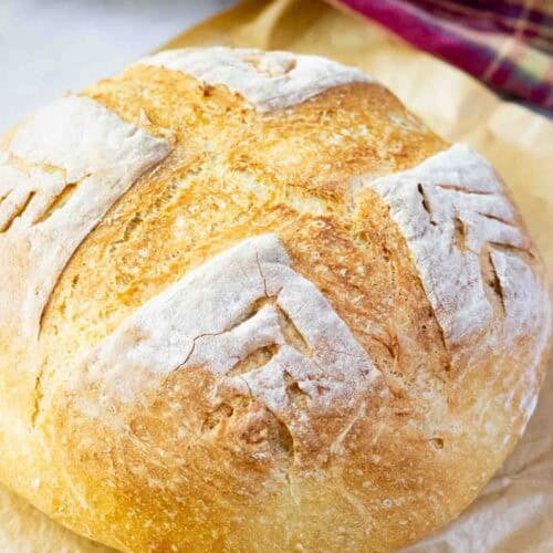 A round crusty bread on a brown parchment paper on a counter