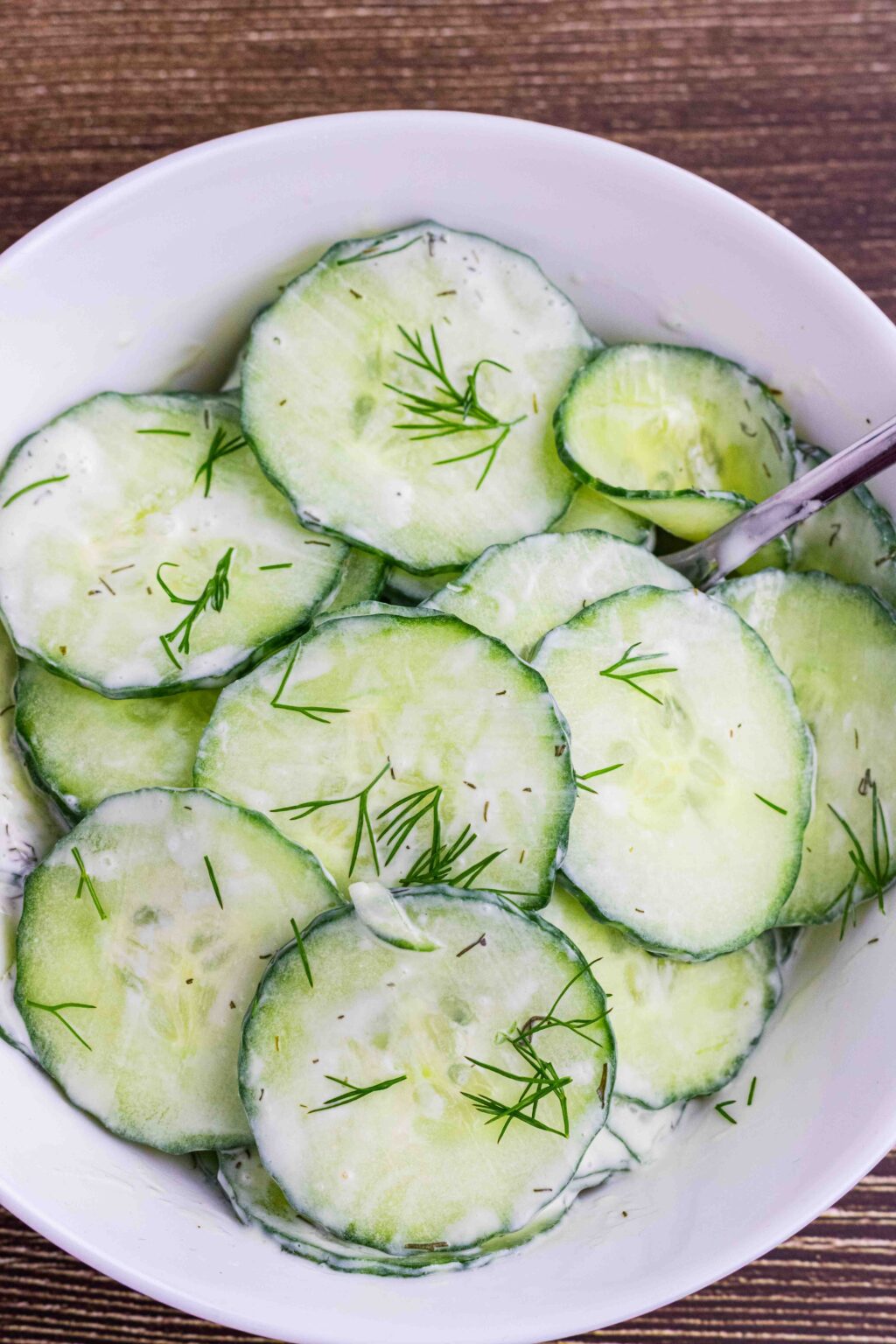 small white bowl with cucumber salad and a fork