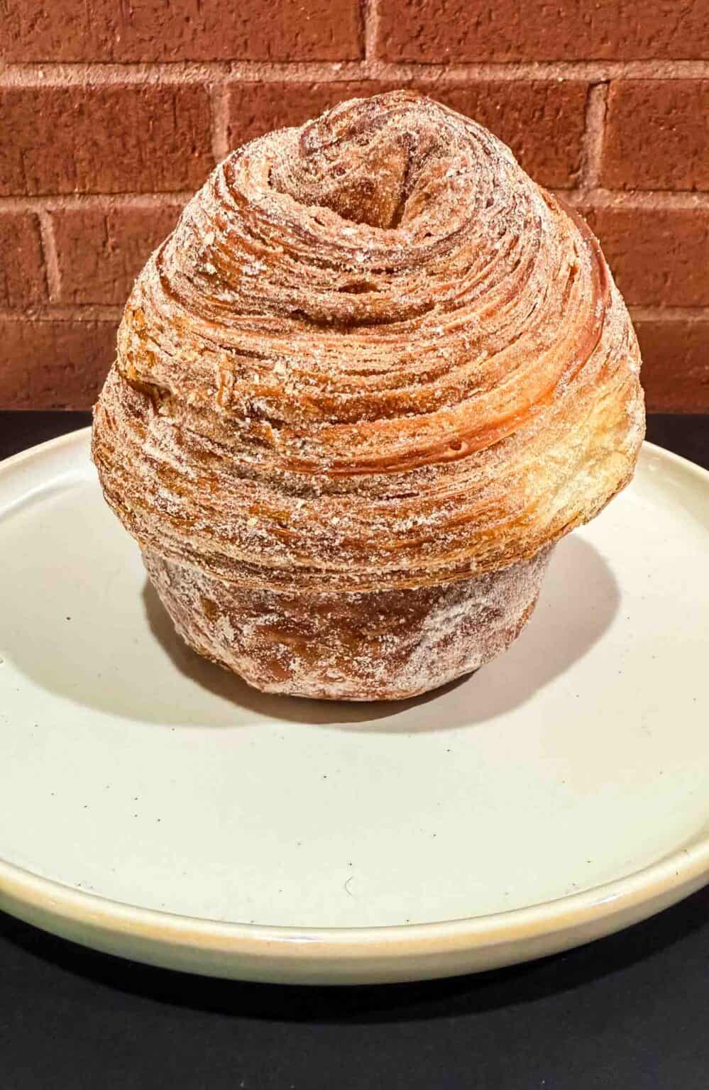 Golden brown cruffin from the front on a white plate