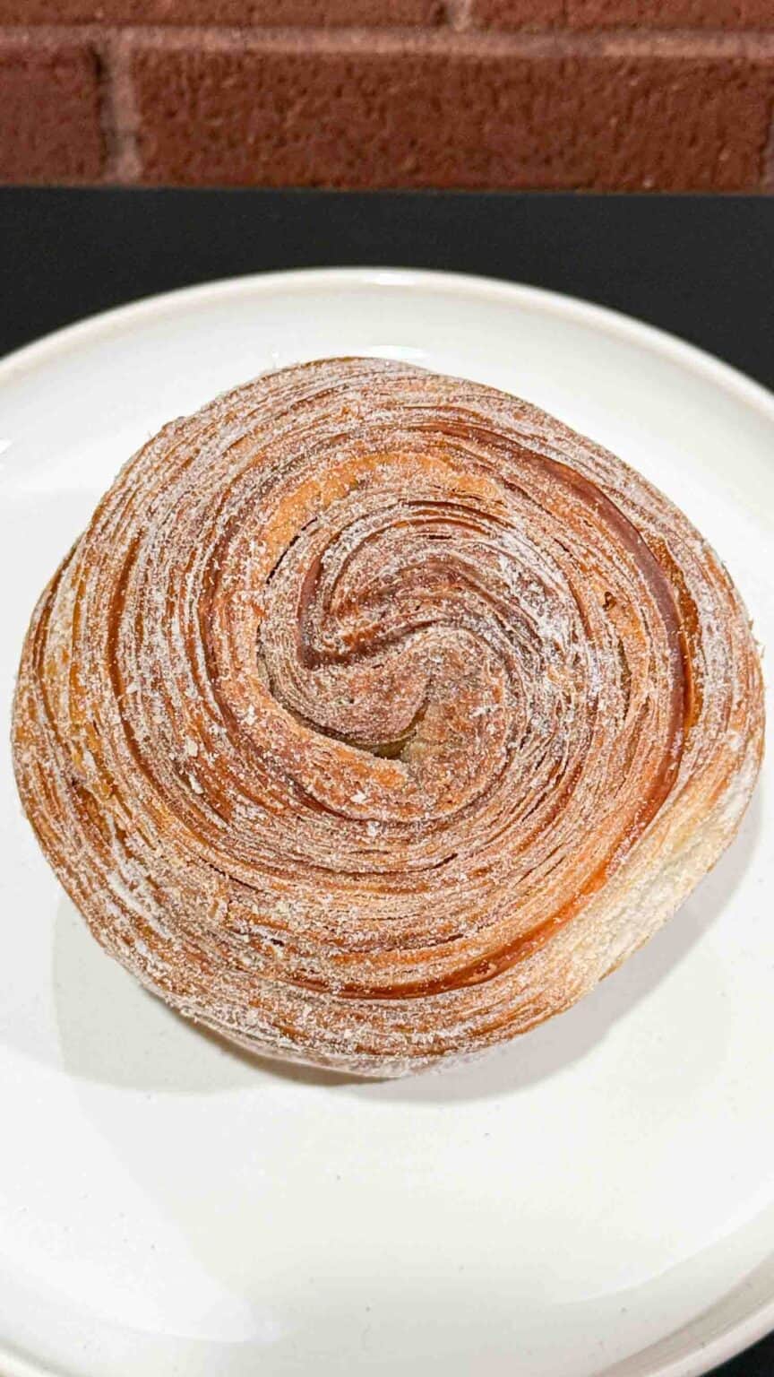 Golden brown top of a cruffin on a white plate