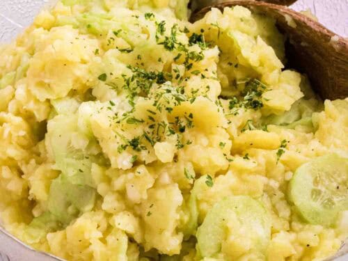 German Potato Salad in a glass bowl with two wooden salad spoons on the side