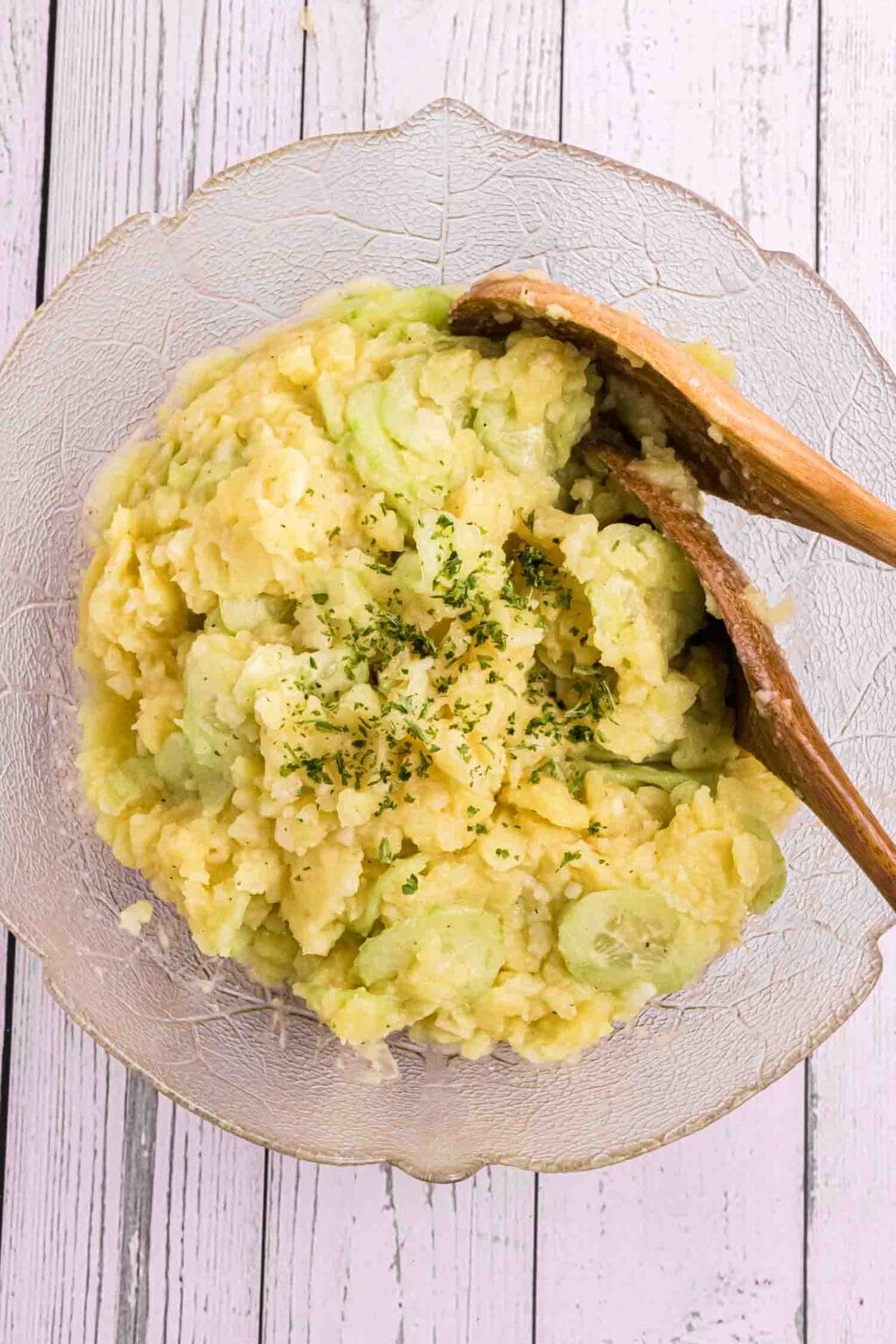 German potato salad with 2 wooden spoons in a glass bowl from Birdseye view