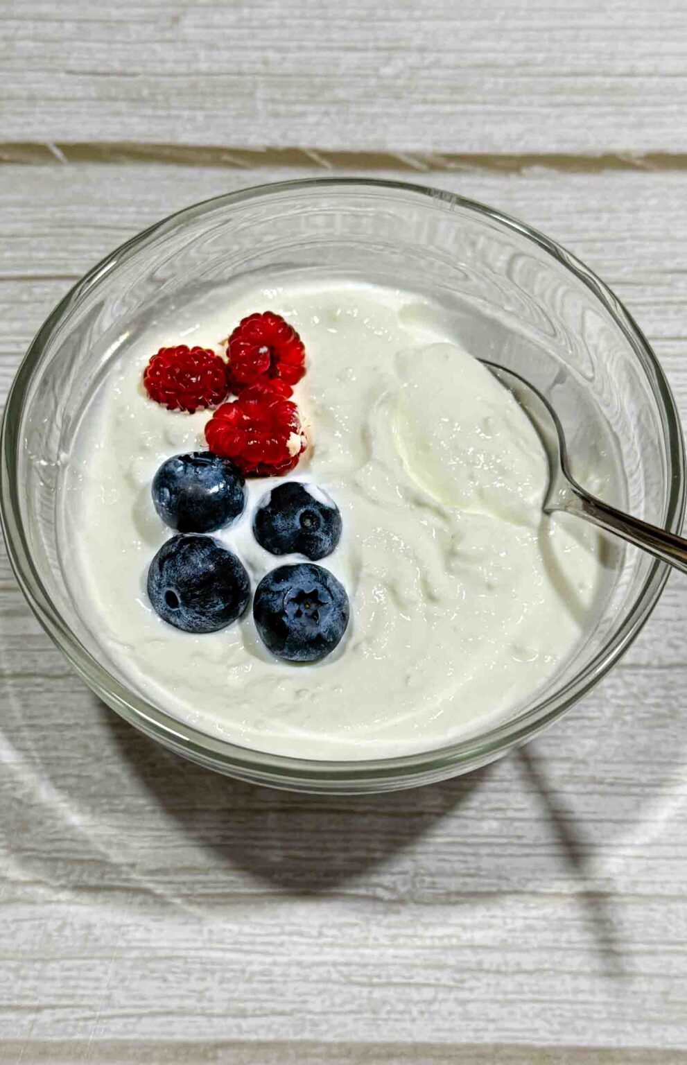 a bowl of plain homemade greek yogurt decorated with blueberries and raspberries