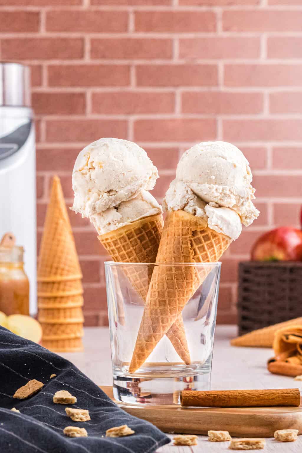 Two ice cream cones with two scoops of Apple Pie Ice Cream held in a glass