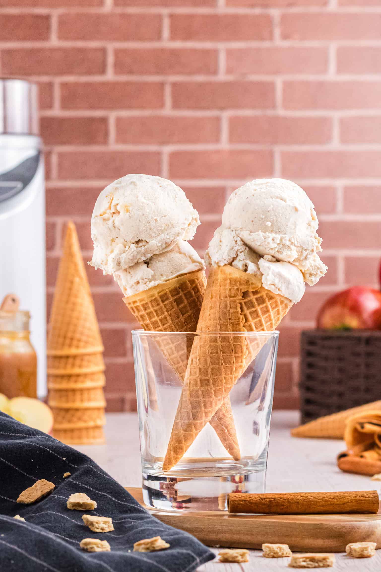 Two ice cream cones with two scoops of Apple Pie Ice Cream held in a glass