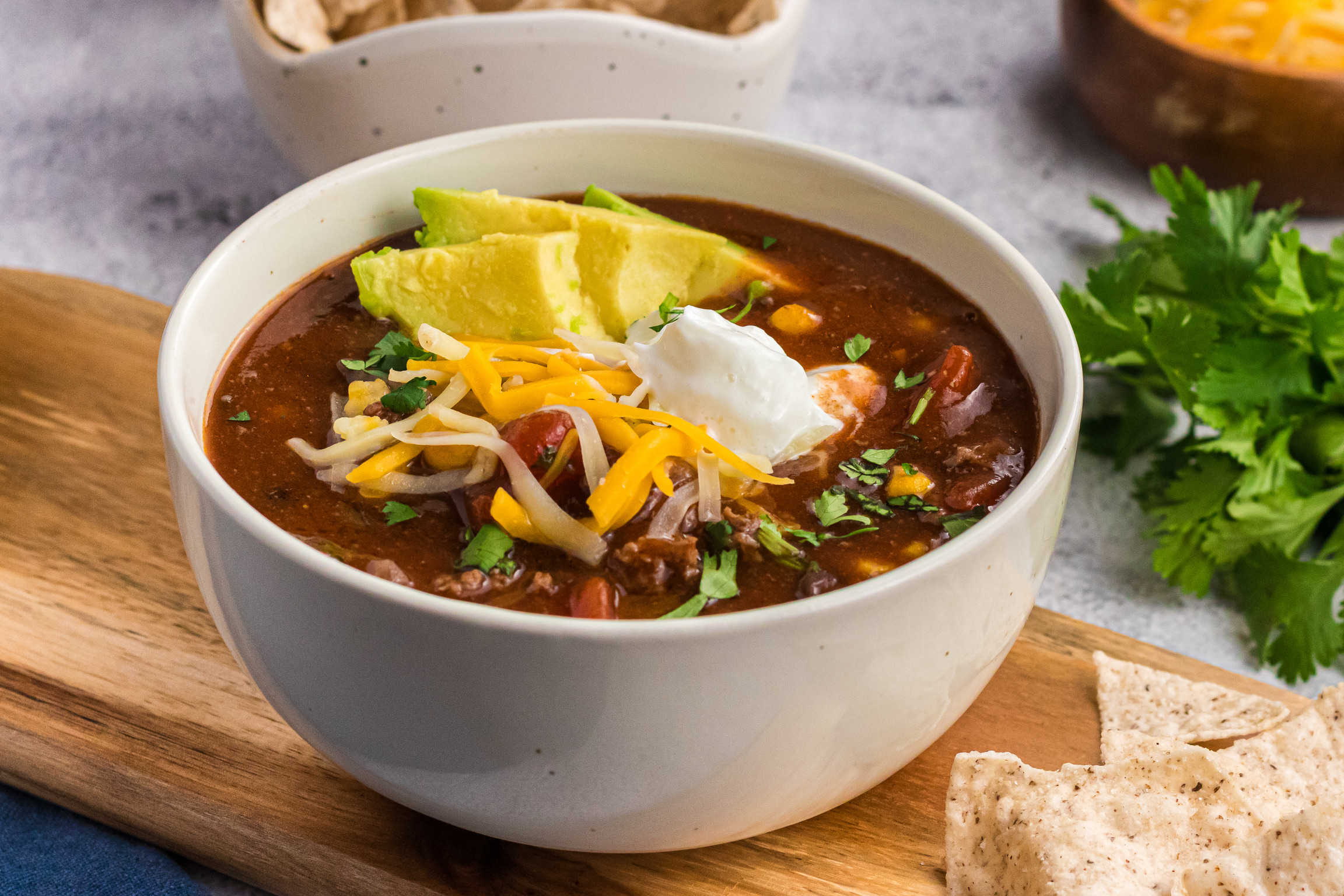 Chili Bowl with finished tasty chili in it ready to eat and topped with cheese, cilantro and sour cream.