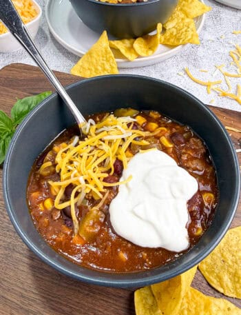 Crockpot Chili in a black bowl topped with sour cream