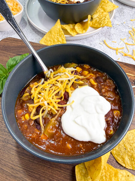 Crockpot Chili in a black bowl topped with sour cream
