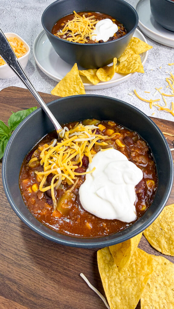 Crockpot Chili in a black bowl topped with sour cream