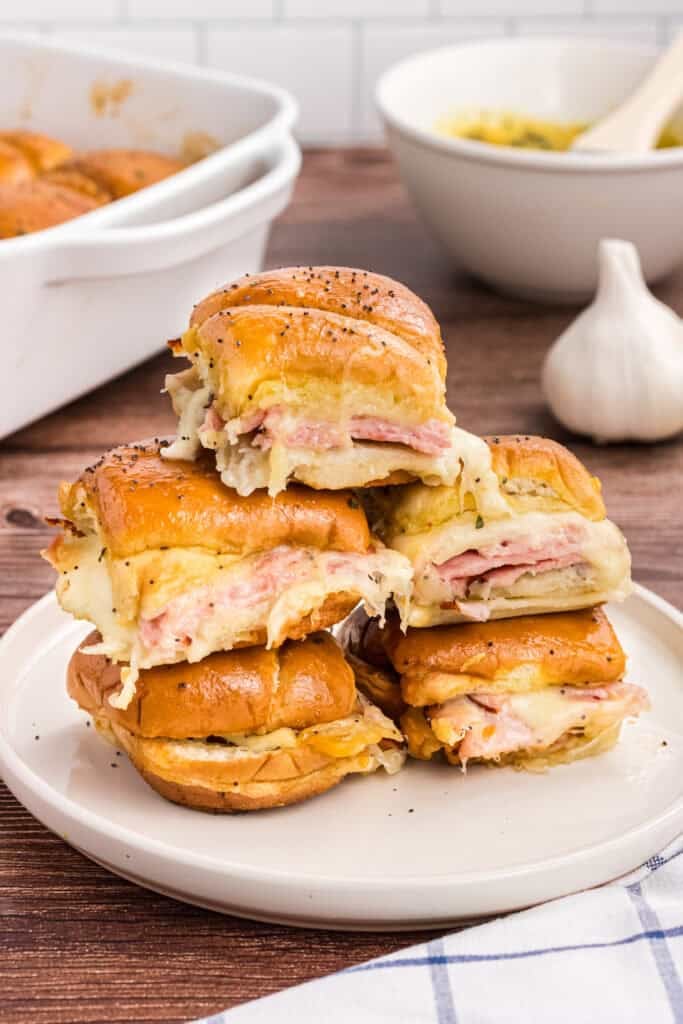 5 stacked ham and cheese sliders on a white plate