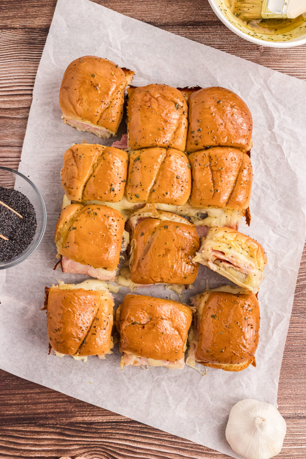 all ham and cheese sliders are place on white parchment paper, but one piece tilted the opposite way