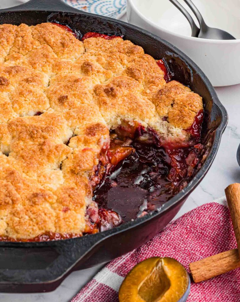plum cobbler with missing piece in cast iron pan. 