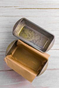 two greased loaf pans laid out with parchment paper