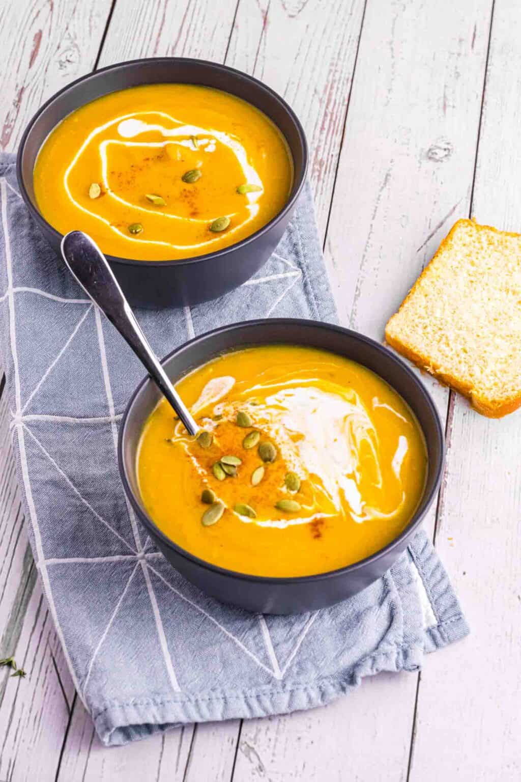 2 bowls of butternut squash soup and sourdough bread on the side