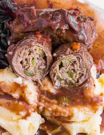 German Beef Rouladen over mashed potatoes, red cabbage and lots of gravy. Cut open so you see pickles and how it is rolled.