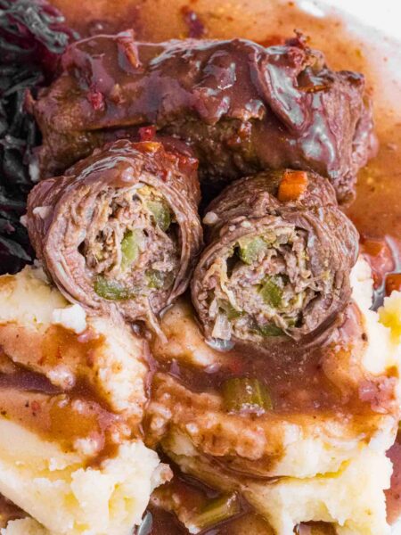 German Beef Rouladen over mashed potatoes, red cabbage and lots of gravy. Cut open so you see pickles and how it is rolled.