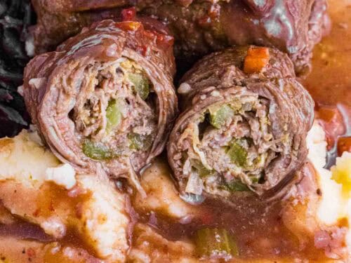 German Beef Rouladen over mashed potatoes, red cabbage and lots of gravy. Cut open so you see pickles and how it is rolled.