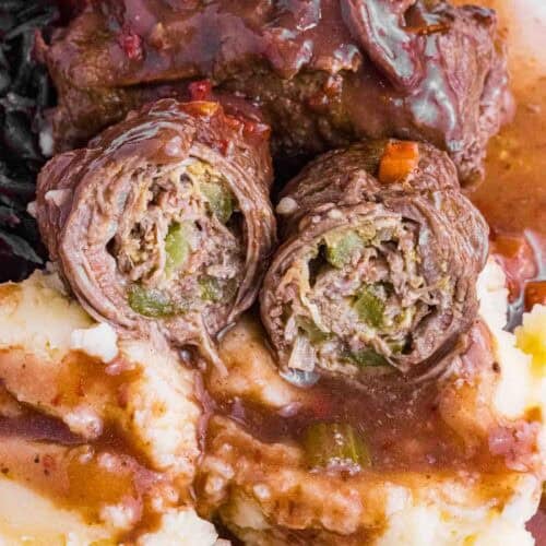 German Beef Rouladen over mashed potatoes, red cabbage and lots of gravy. Cut open so you see pickles and how it is rolled.