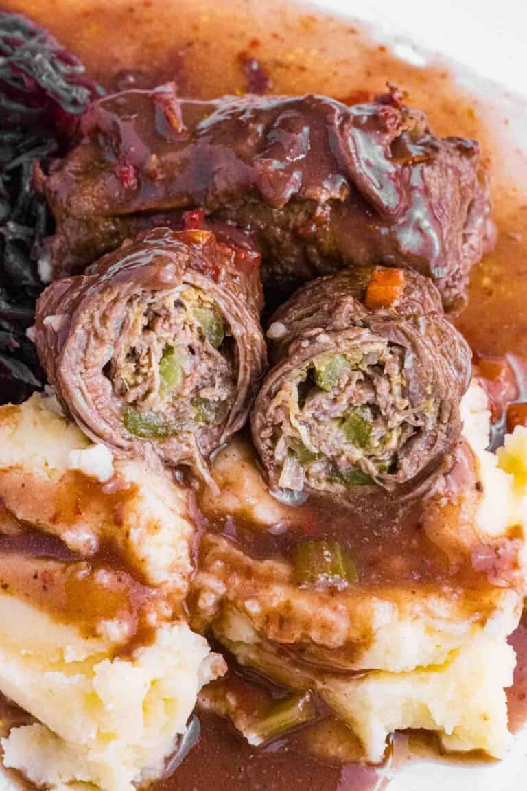 German Beef Rouladen over mashed potatoes, red cabbage and lots of gravy. Cut open so you see pickles and how it is rolled.