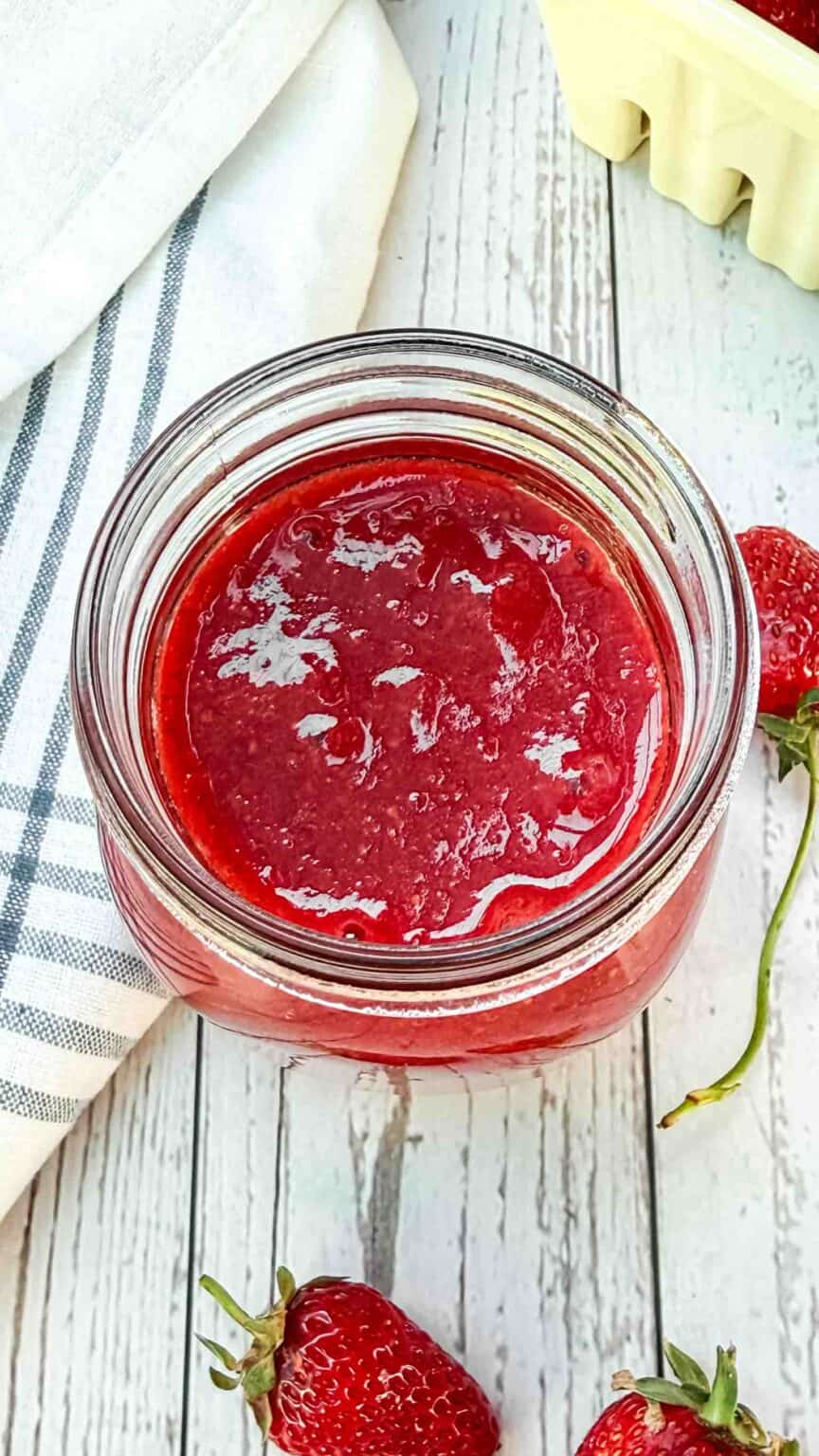 look into the opening of a mason jar and straight at some red smooth strawberry sauce