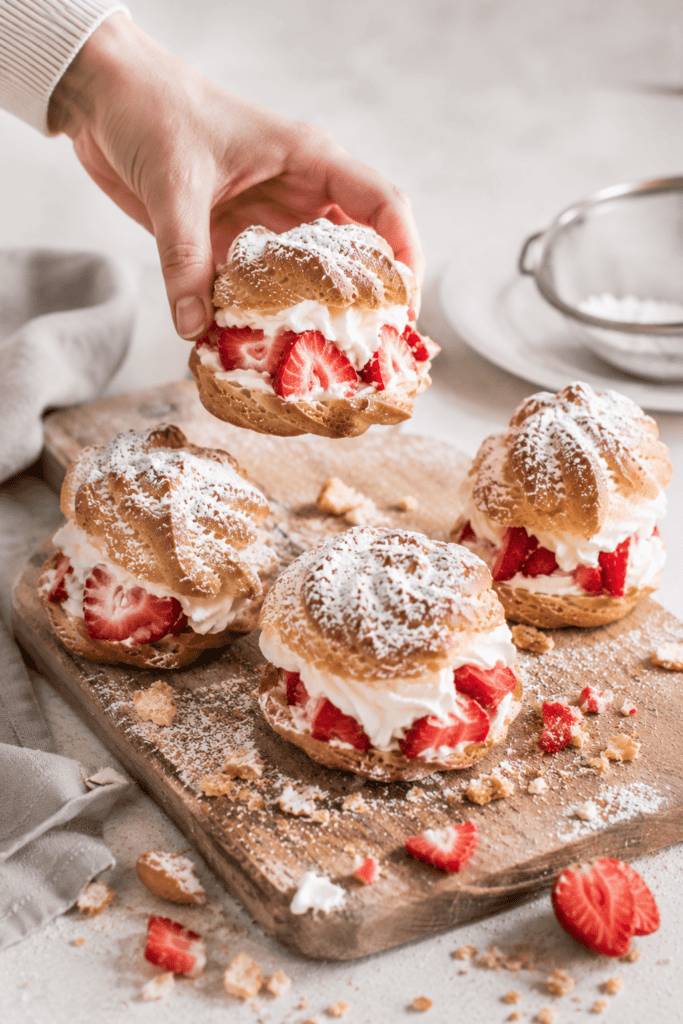a hand snatching a German strawberry windbeutel or cream puff