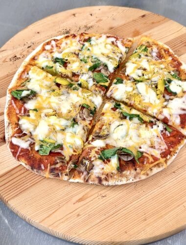 grilled pizza on a round wooden board cut in 4 pieces
