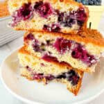 Stacked up blueberry cake squares on a white plate. 3 cake squares high