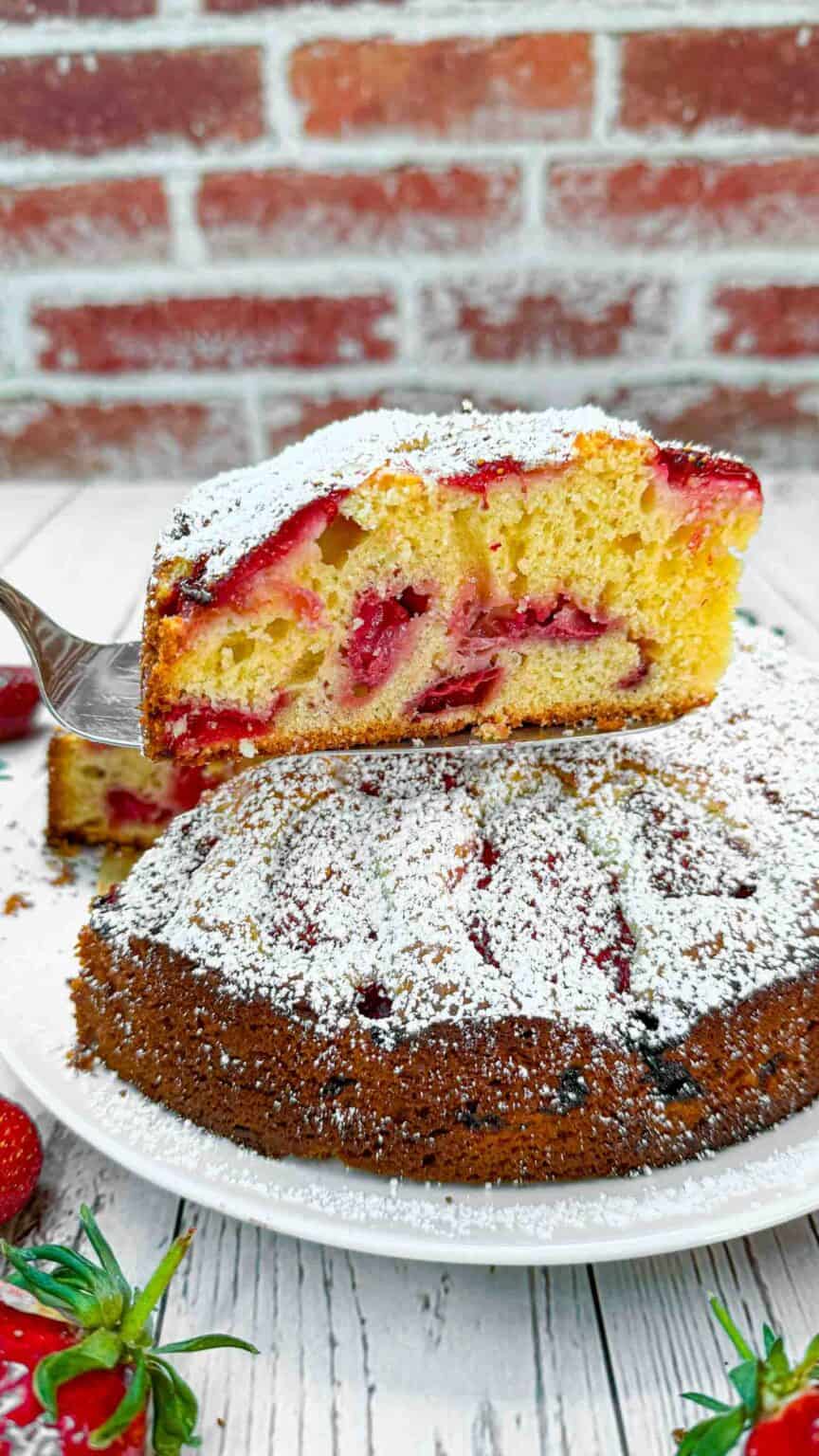 strawberry cake slice on spatula over cake