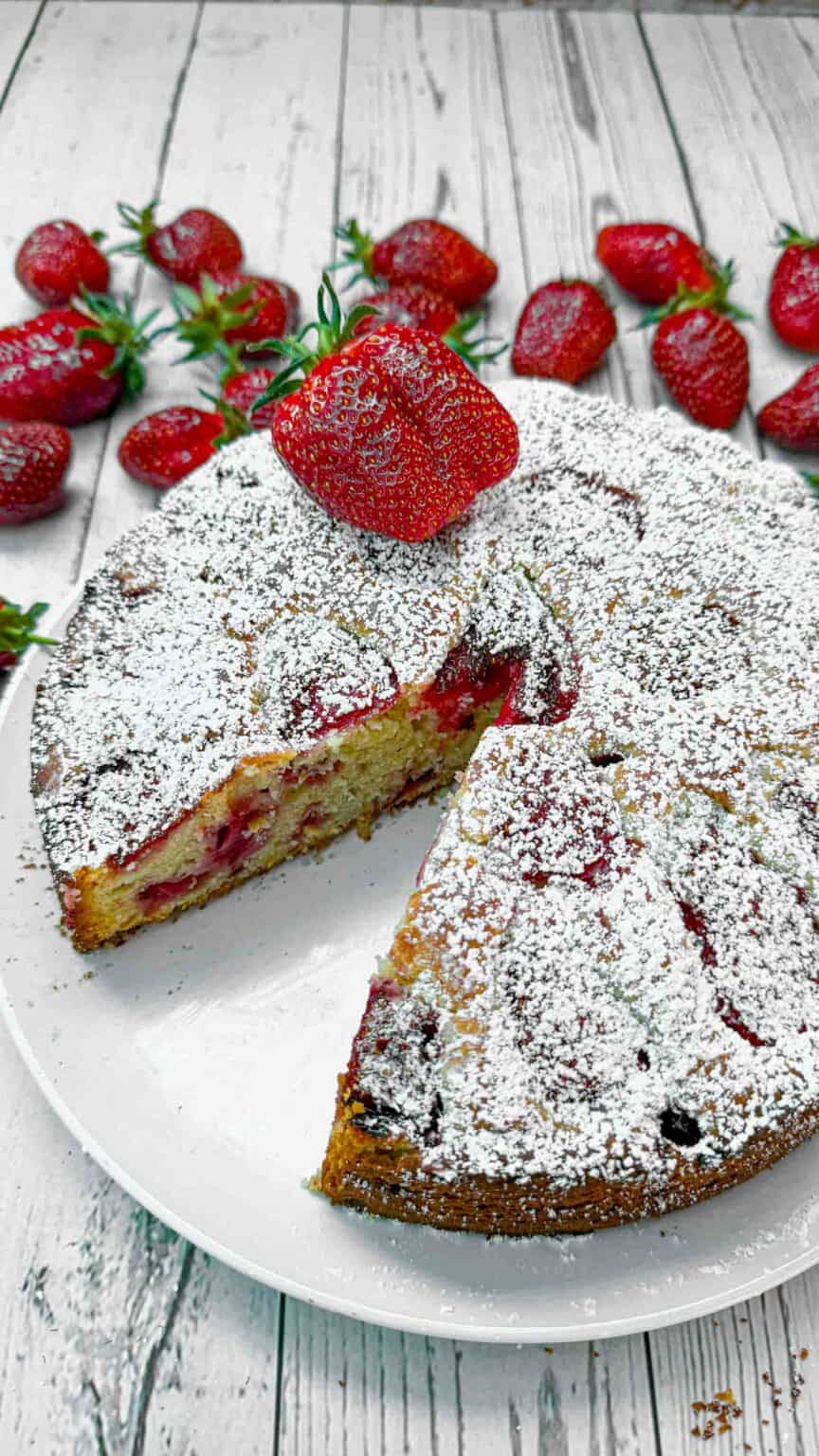 Strawberry cake with a slice missing and a big strawberry on top