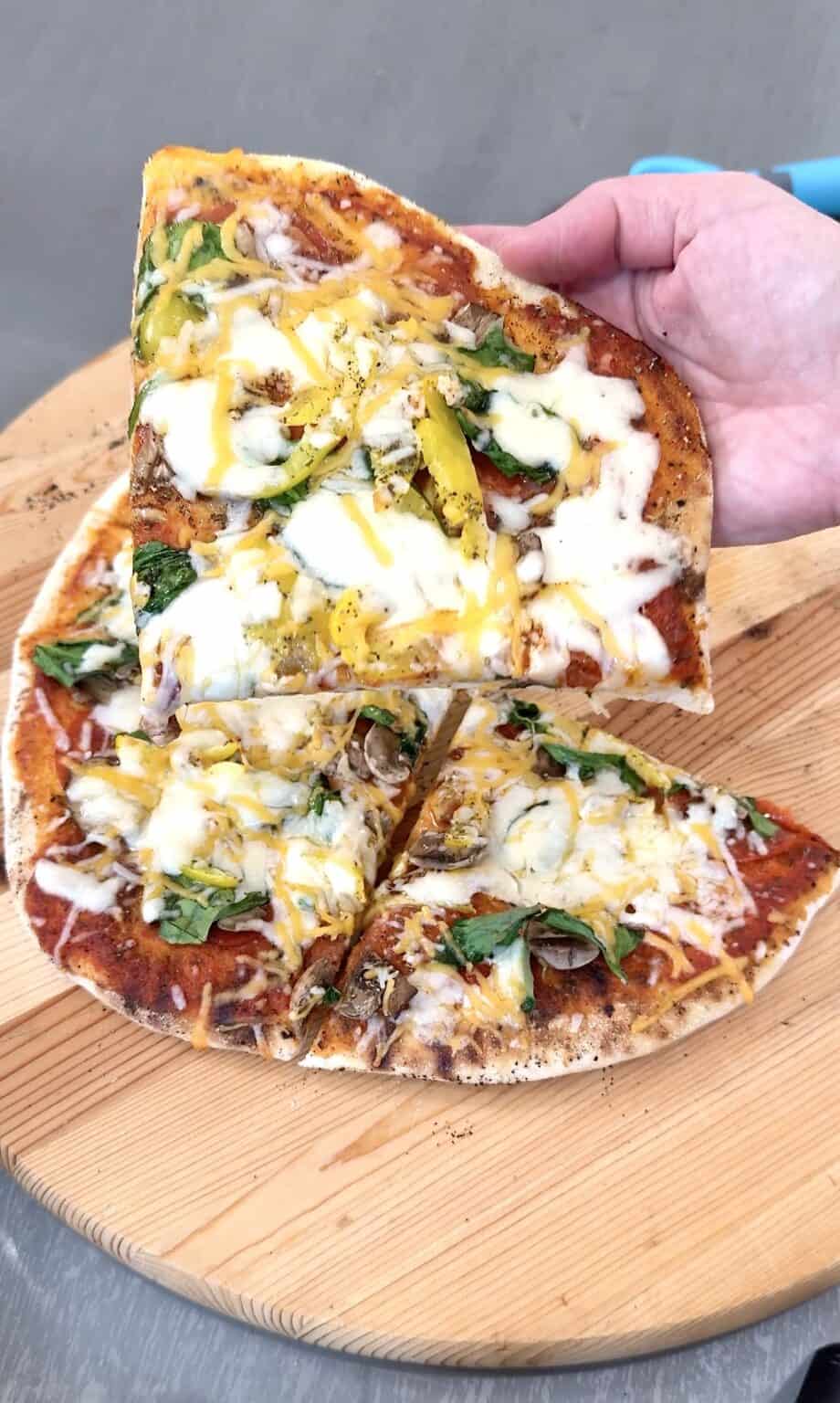 grilled pizza slice held in hand