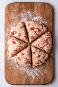 strawberry scones cut equally in 6 pieces on a wooden board