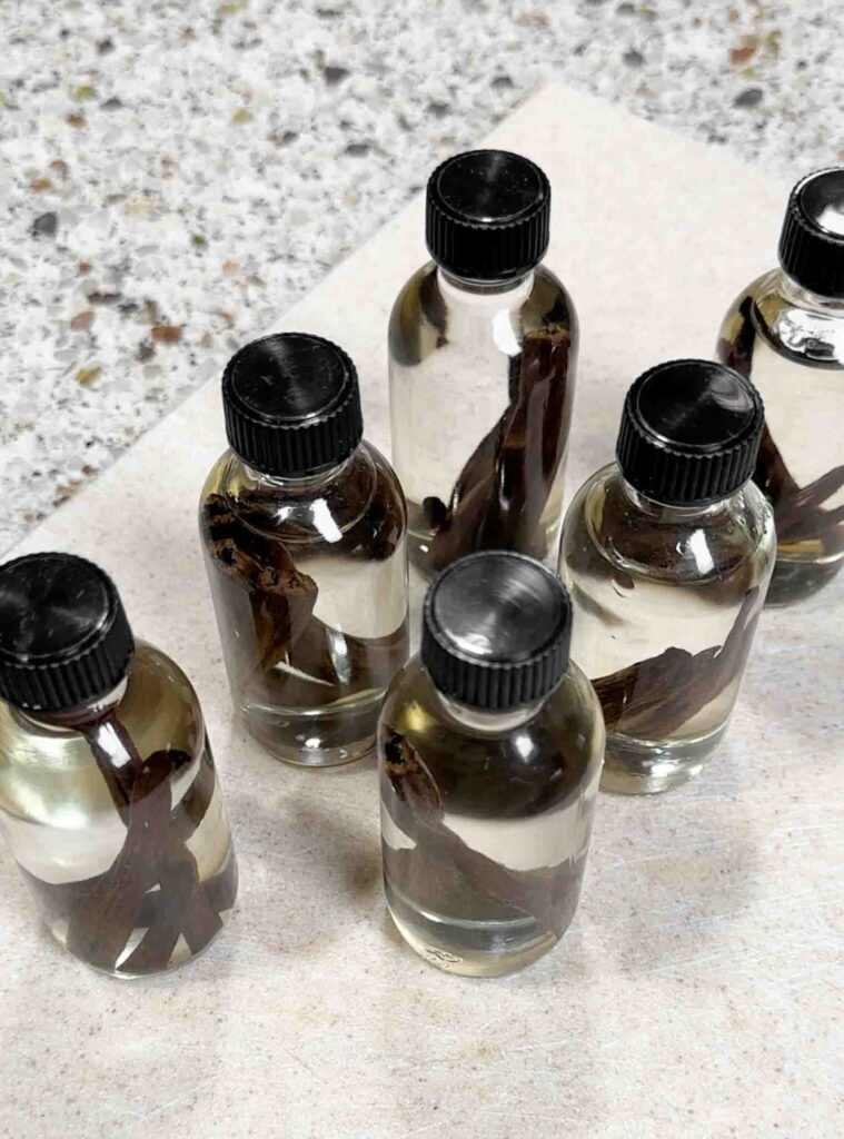 6 small bottles filled with vodka and vanilla beans